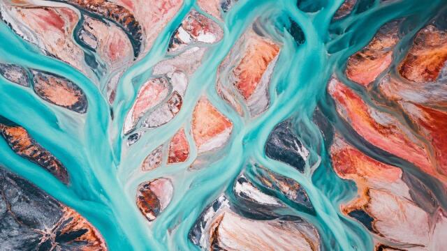 Turquoise river channels cross coral-colored sediment islands in an aerial view for QUIQQER 2.28